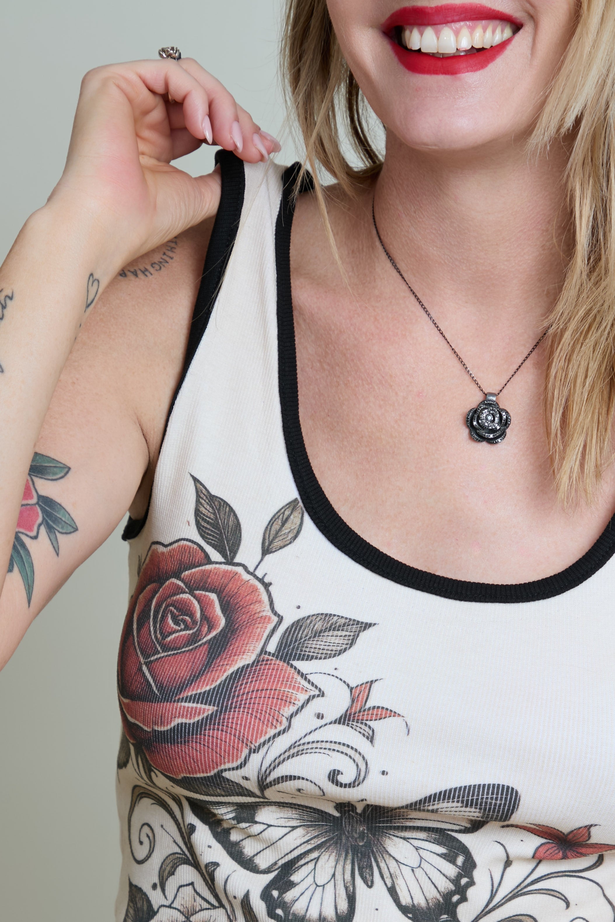 Person wearing a tank top with floral designs and a necklace.