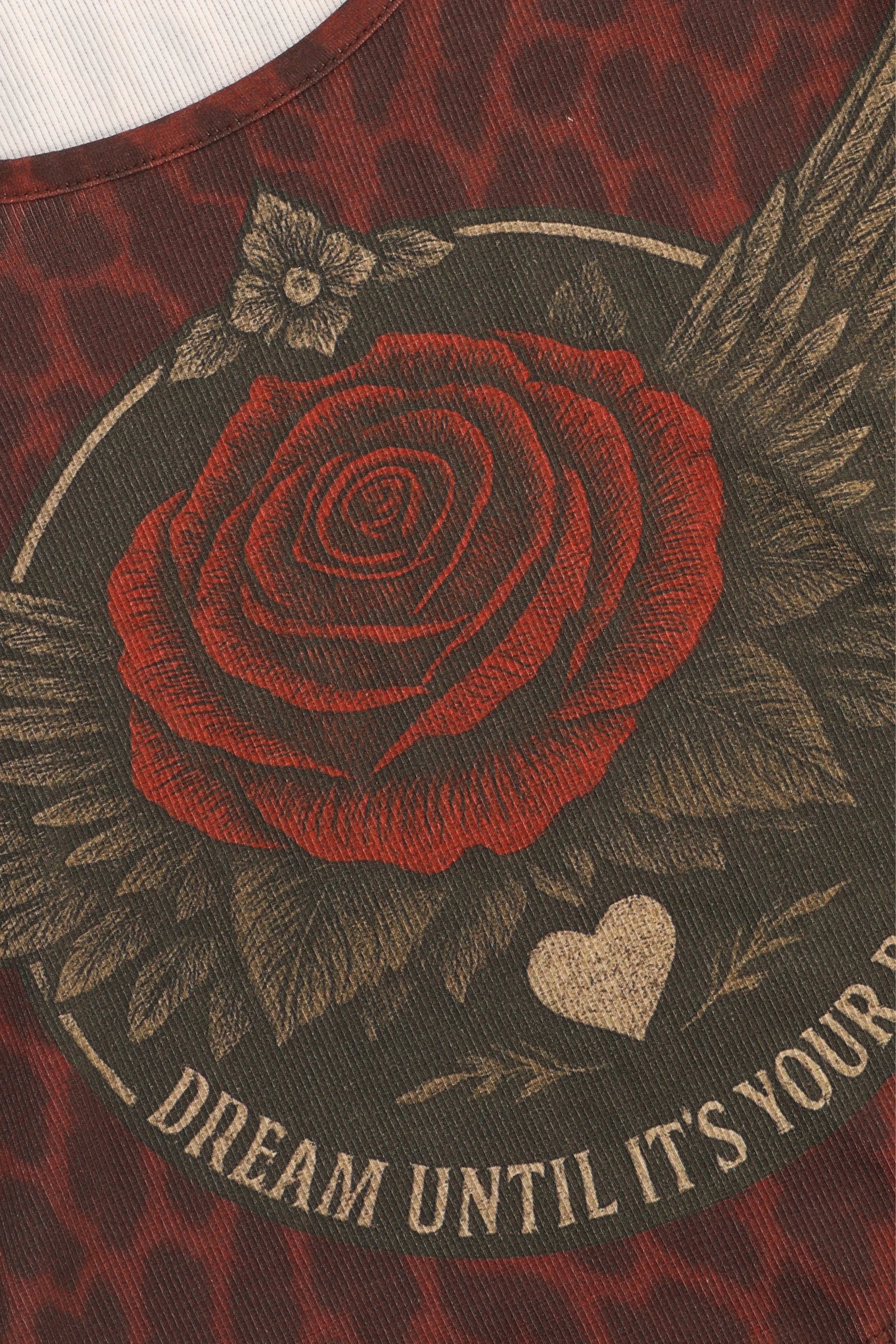 Embroidered red rose with leaves and a heart on a garment with text.