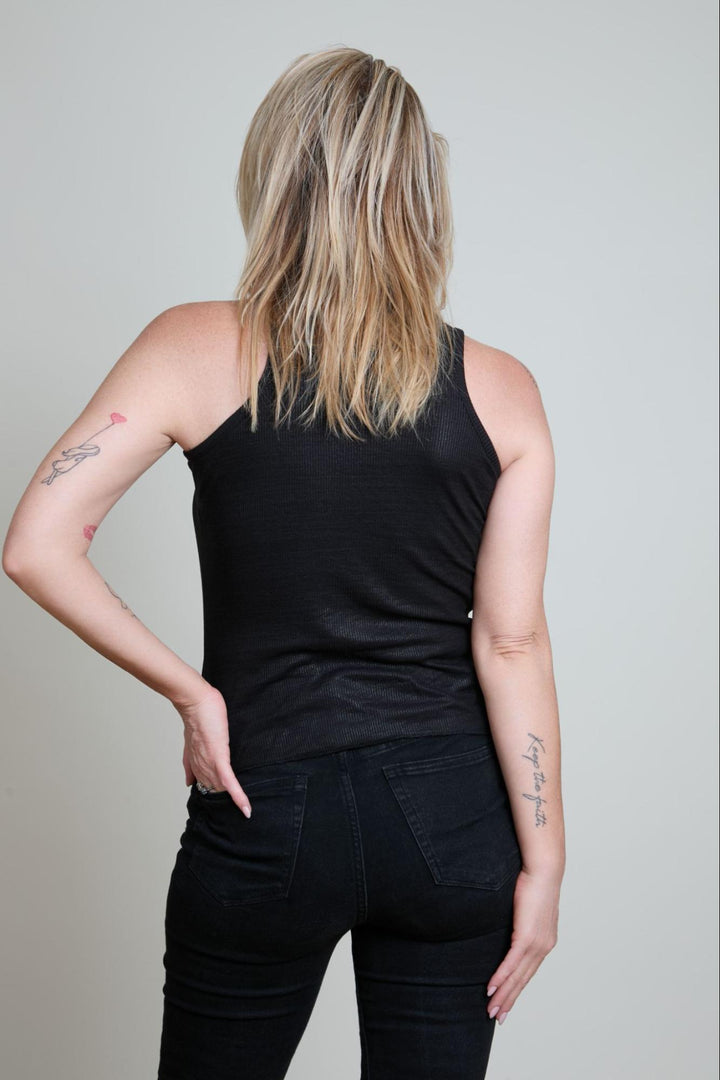 Person wearing a black tank top and black pants against a plain background