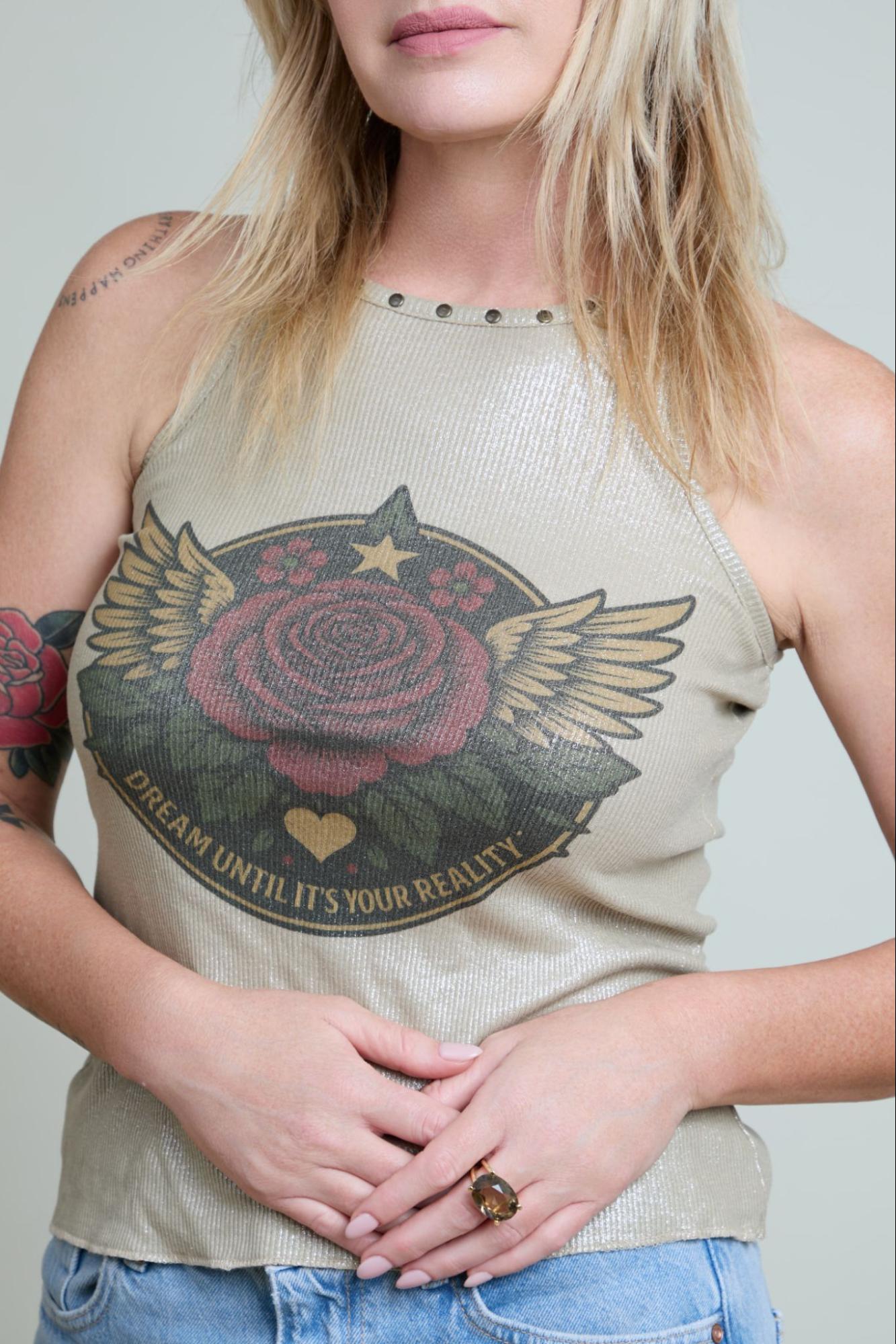 Person wearing a beige tank top with a graphic design of a rose with wings and text.
