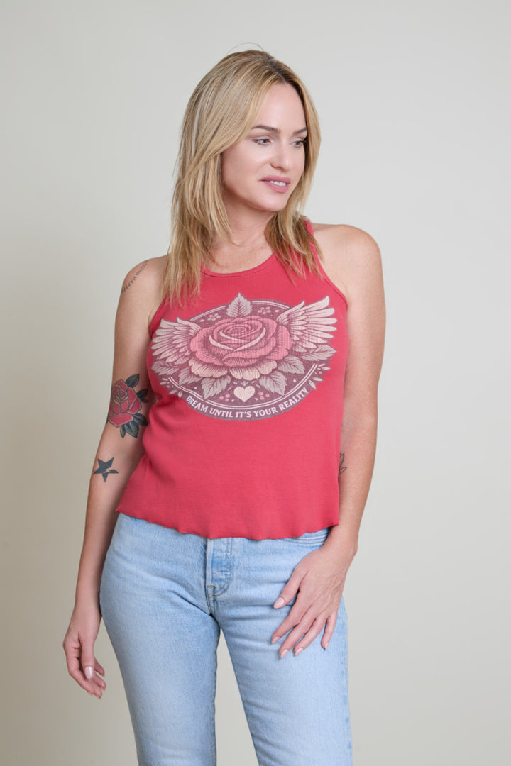 Woman wearing a red tank top with a floral design and light blue jeans on a beige background
