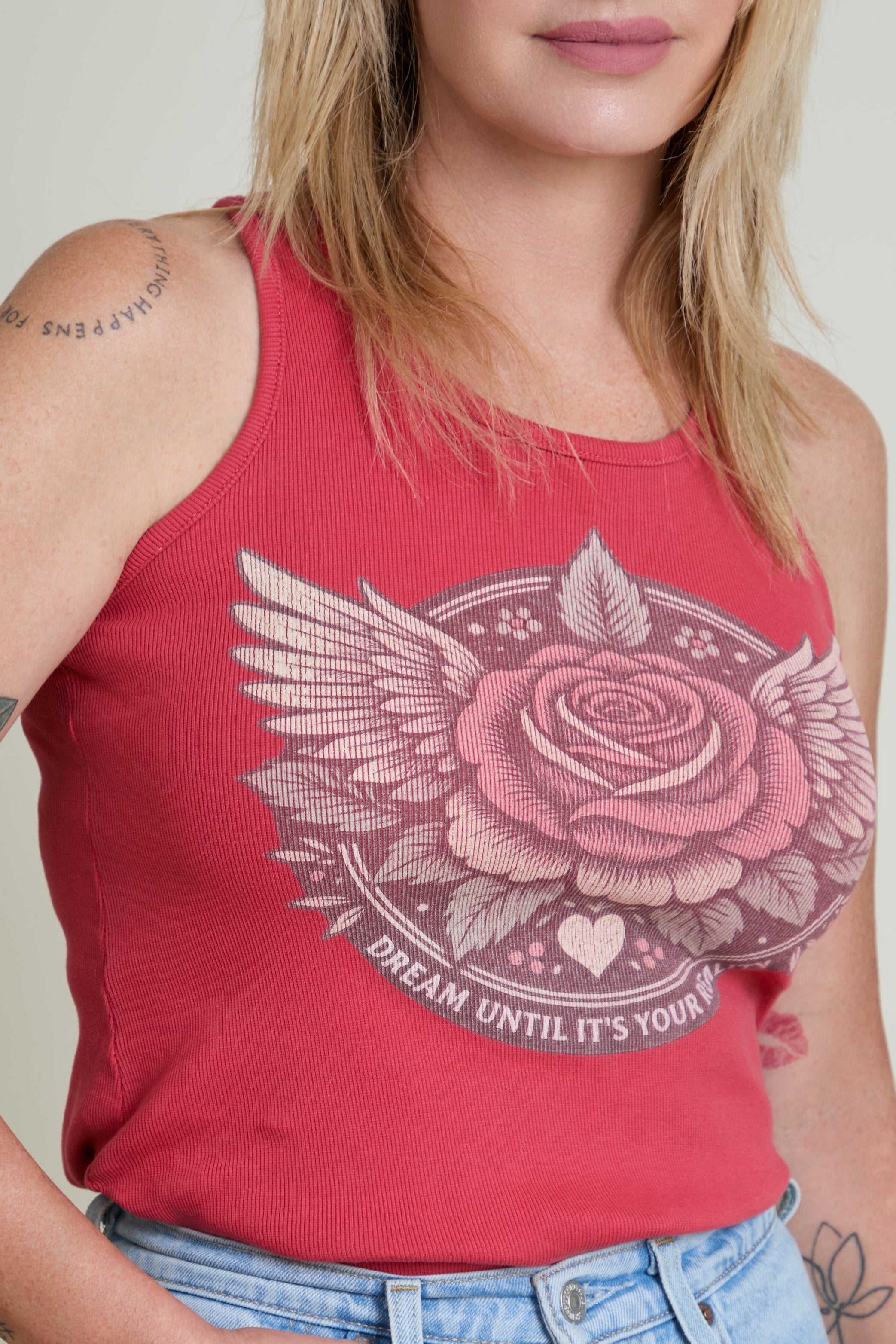 Red tank top with a rose and wing design and text on a plain background