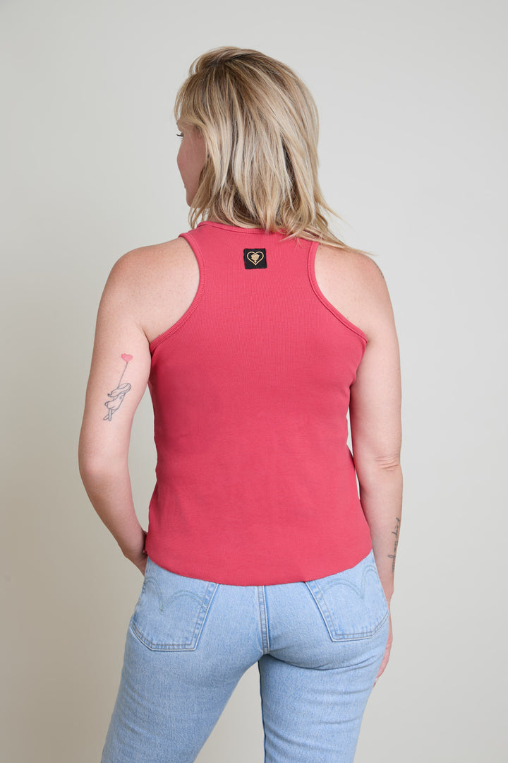 Person wearing a red tank top and light blue jeans on a plain background