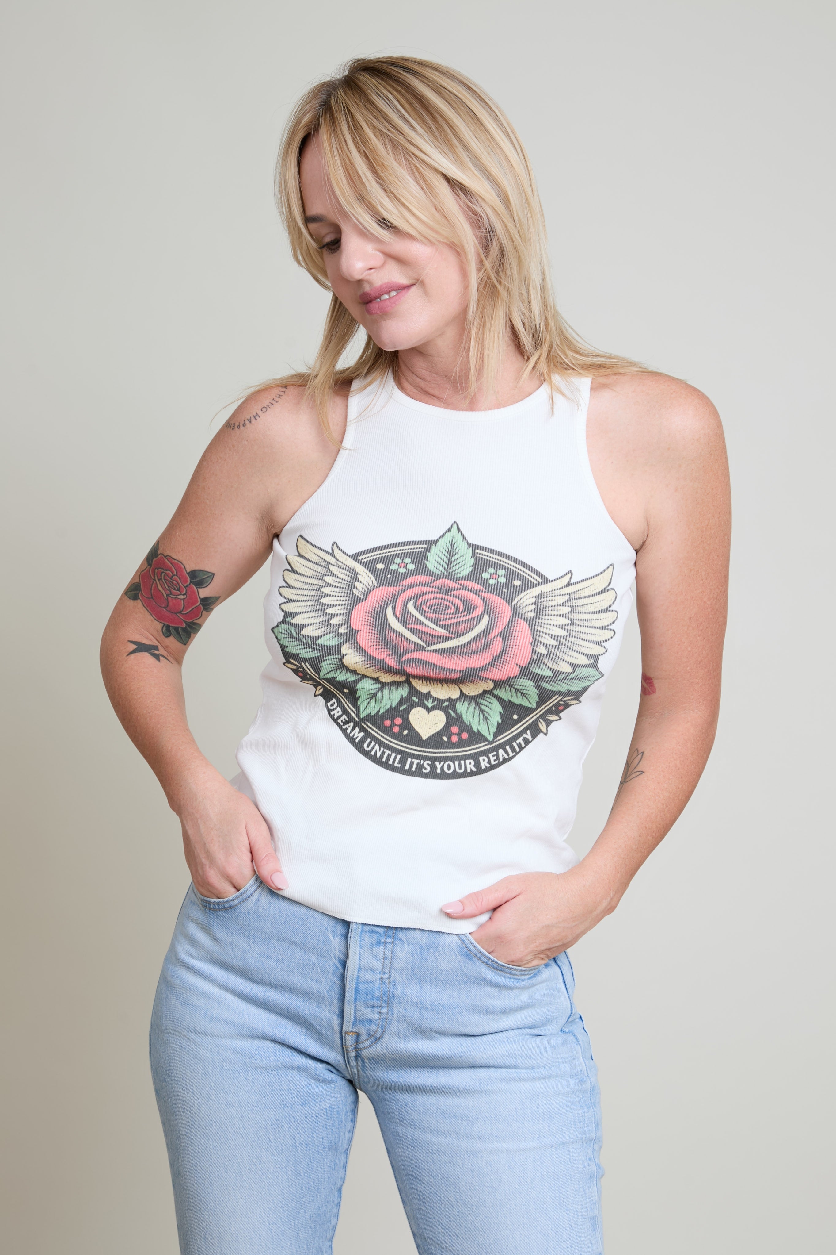 Woman wearing a white tank top with a colorful graphic design on a plain background