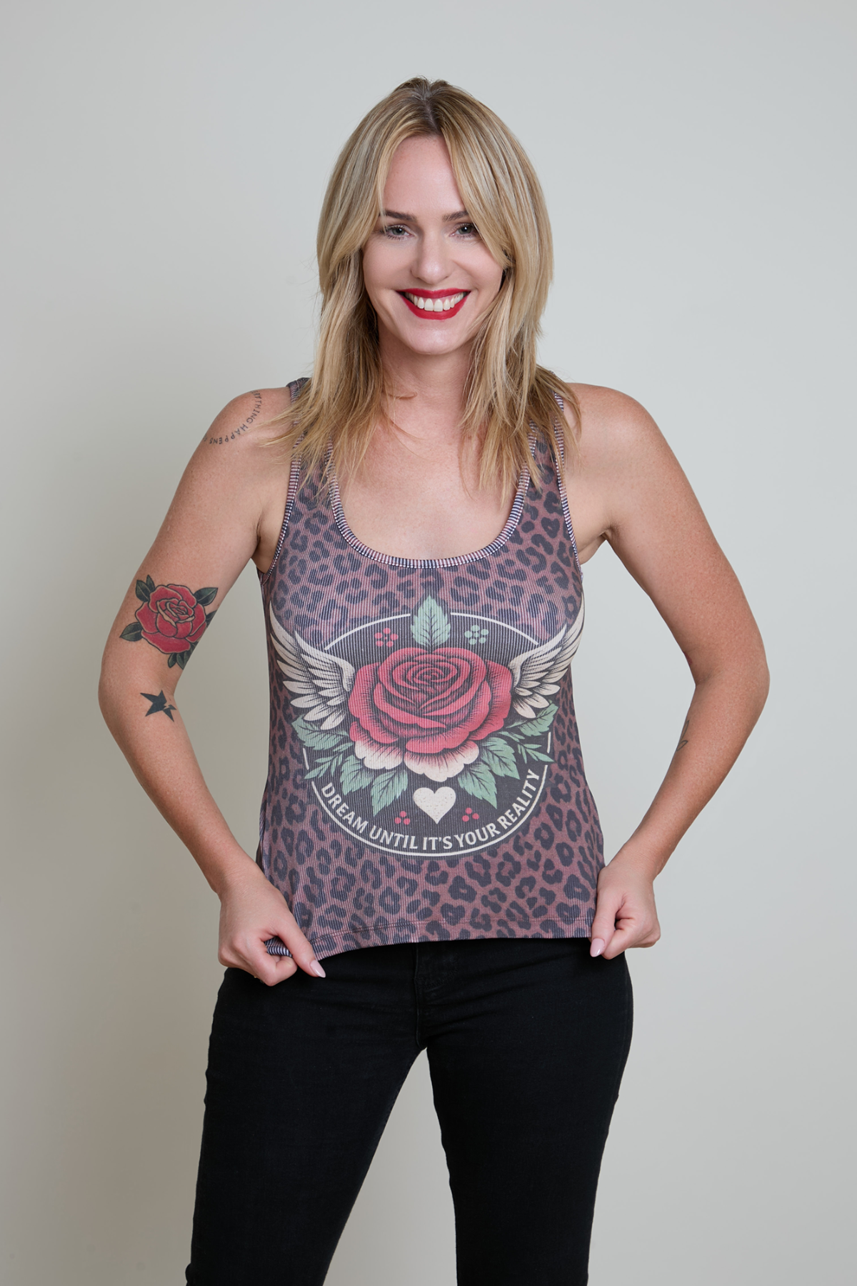 Woman wearing a tank top with a rose design on a plain background