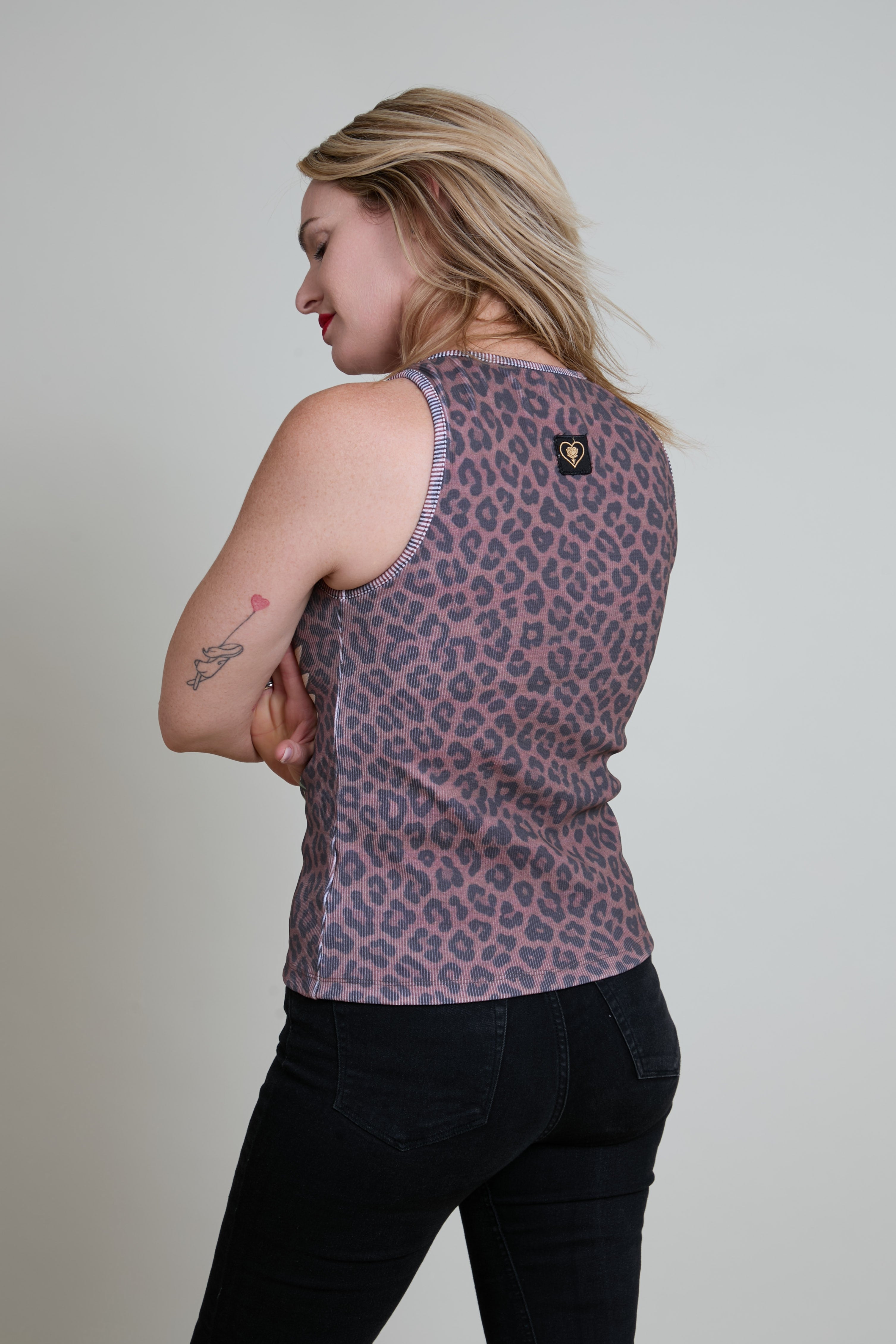 Woman wearing a leopard print tank top with a plain background