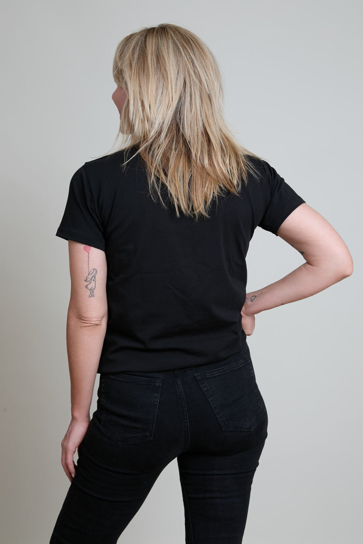 Person wearing a black t-shirt and black pants against a plain background