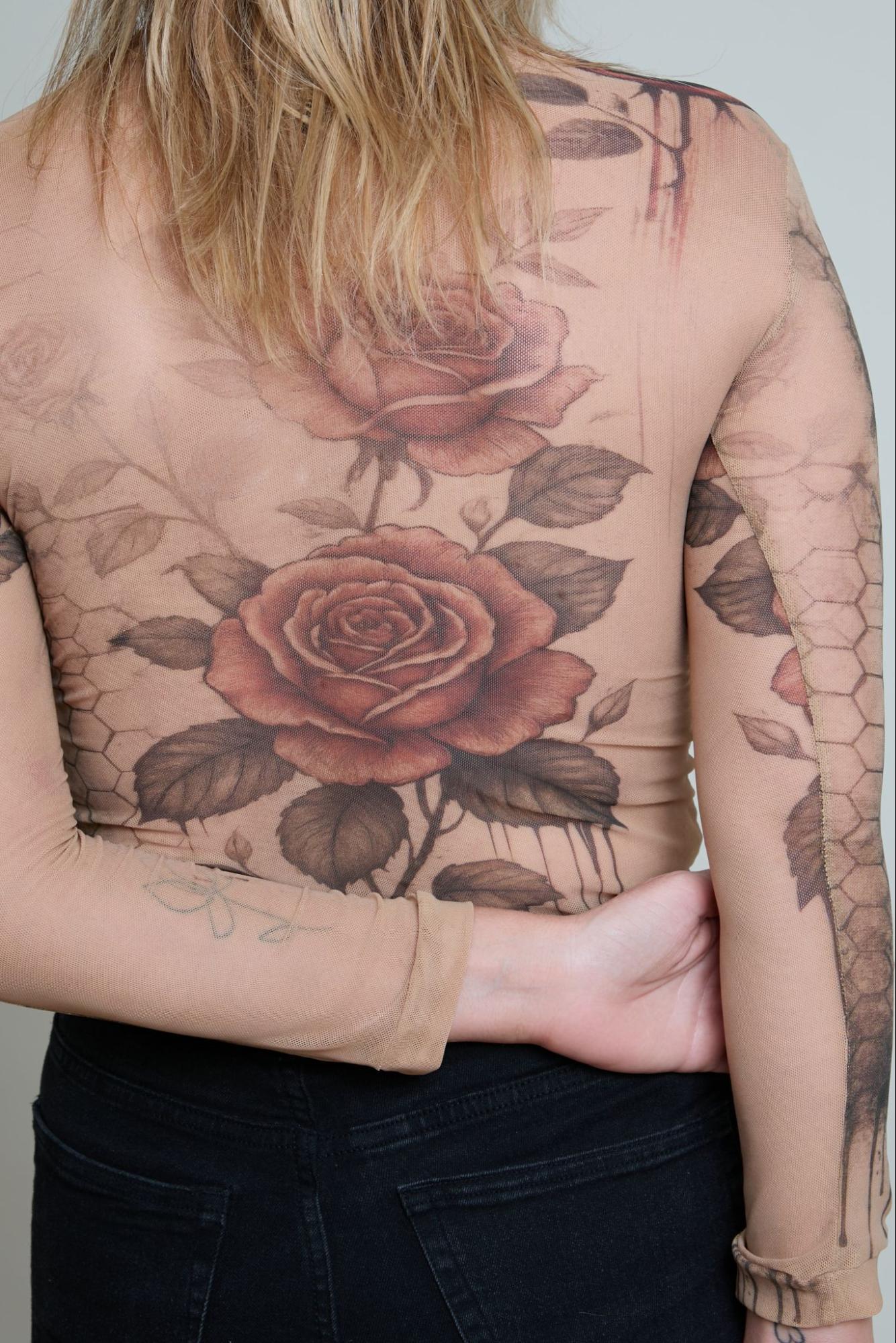 Person with detailed rose tattoos on their back and arm against a neutral background