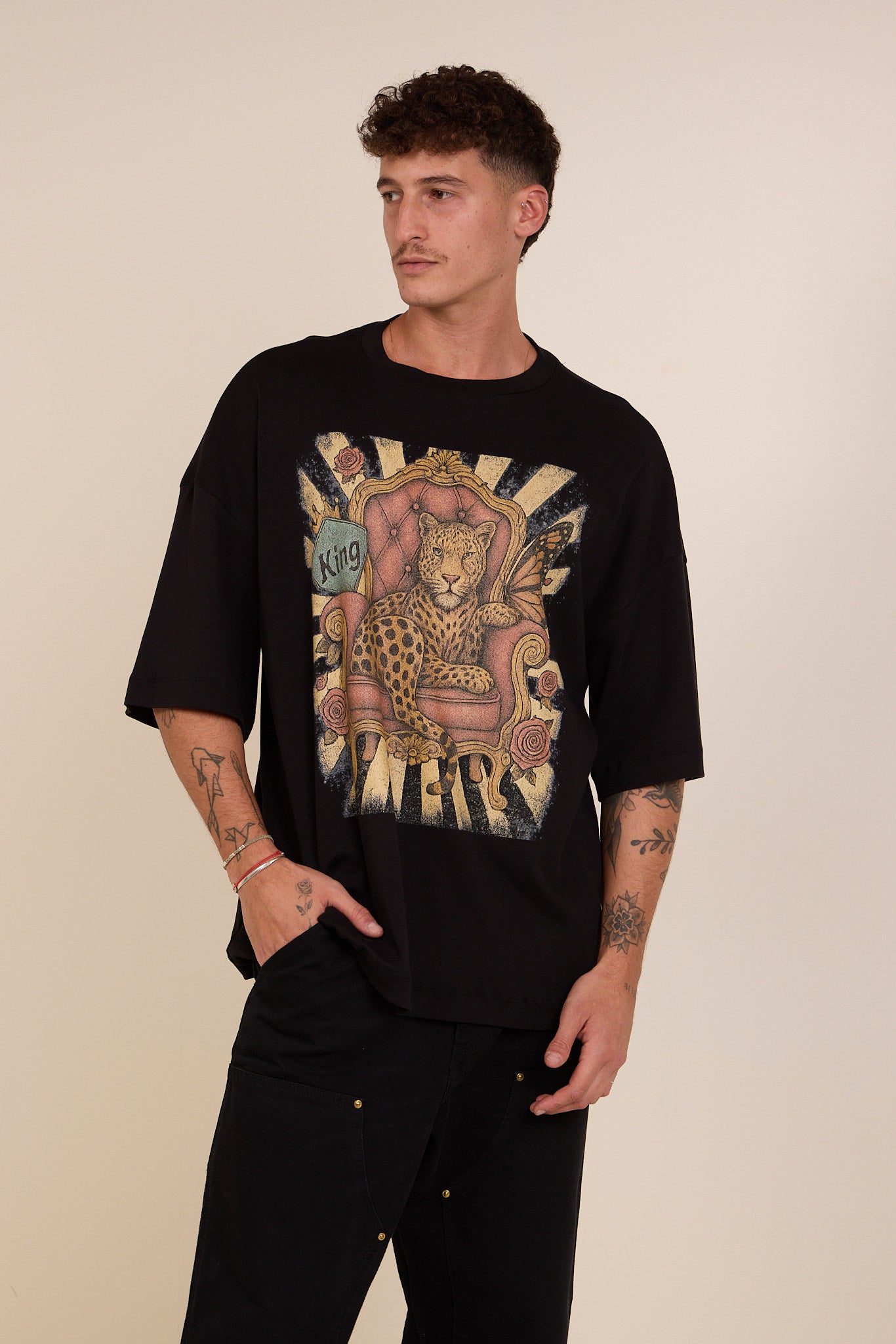 Man wearing a black t-shirt with a graphic design on a beige background