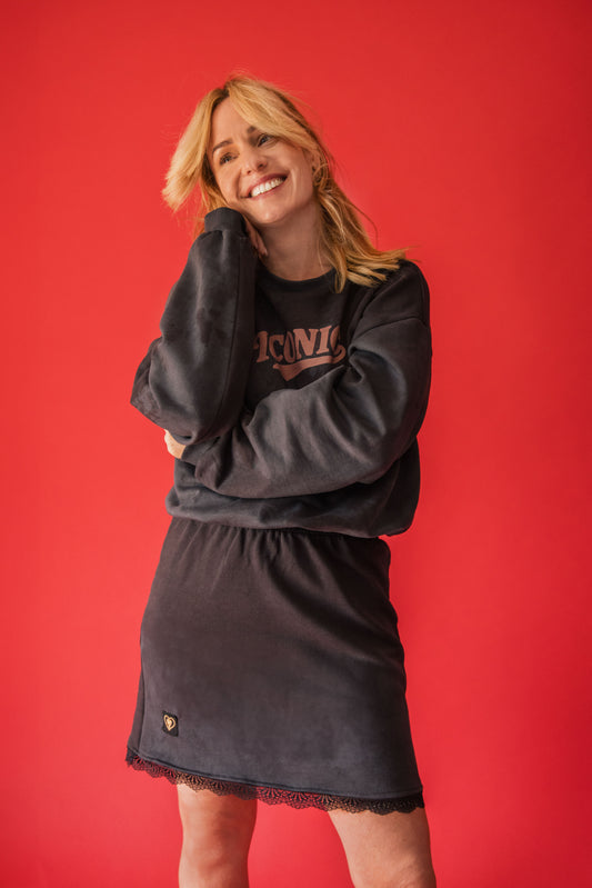 Woman wearing a black sweatshirt and skirt set with 'ICARE' text on a red background