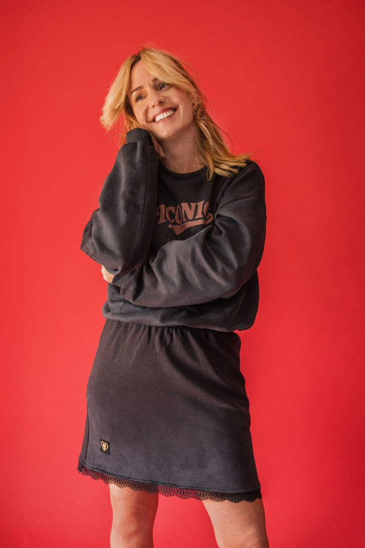 Woman wearing a black sweatshirt and skirt set with 'ICARE' text on a red background