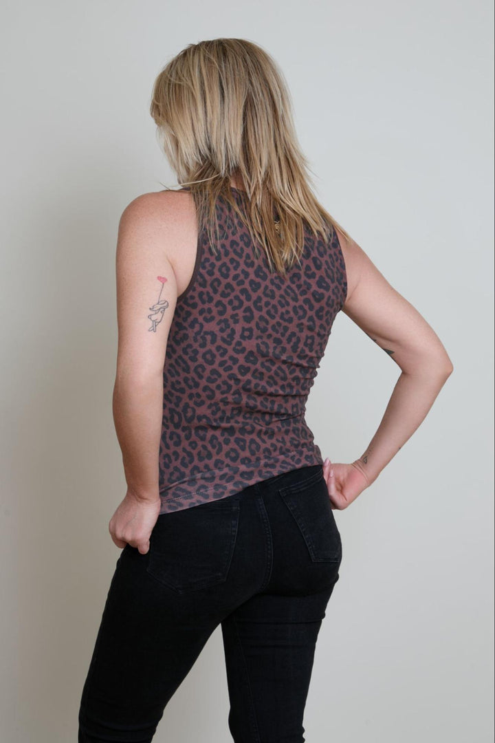 Person wearing a sleeveless top with a leopard print pattern against a plain background