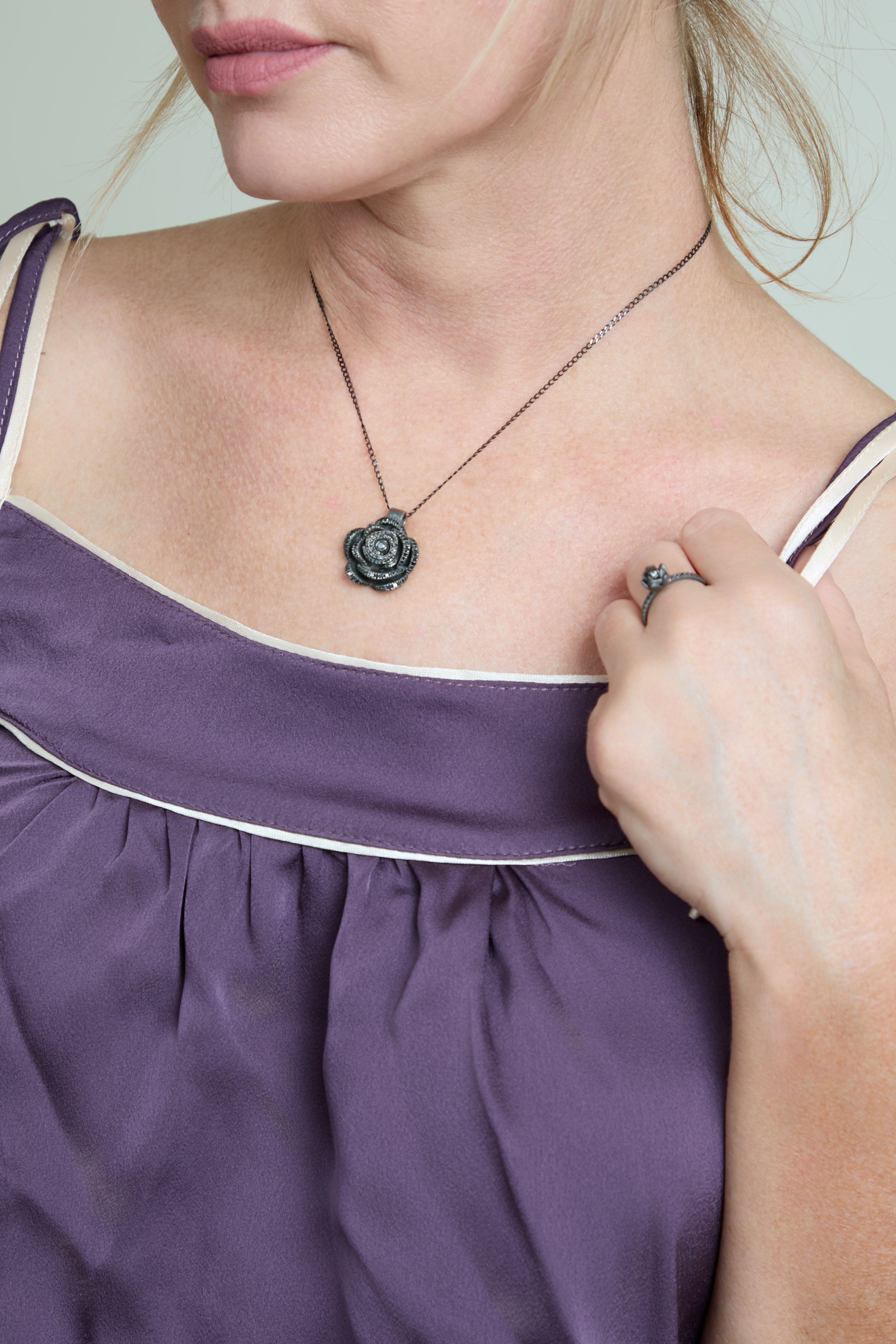 Woman wearing a purple dress with a necklace featuring a rose pendant.