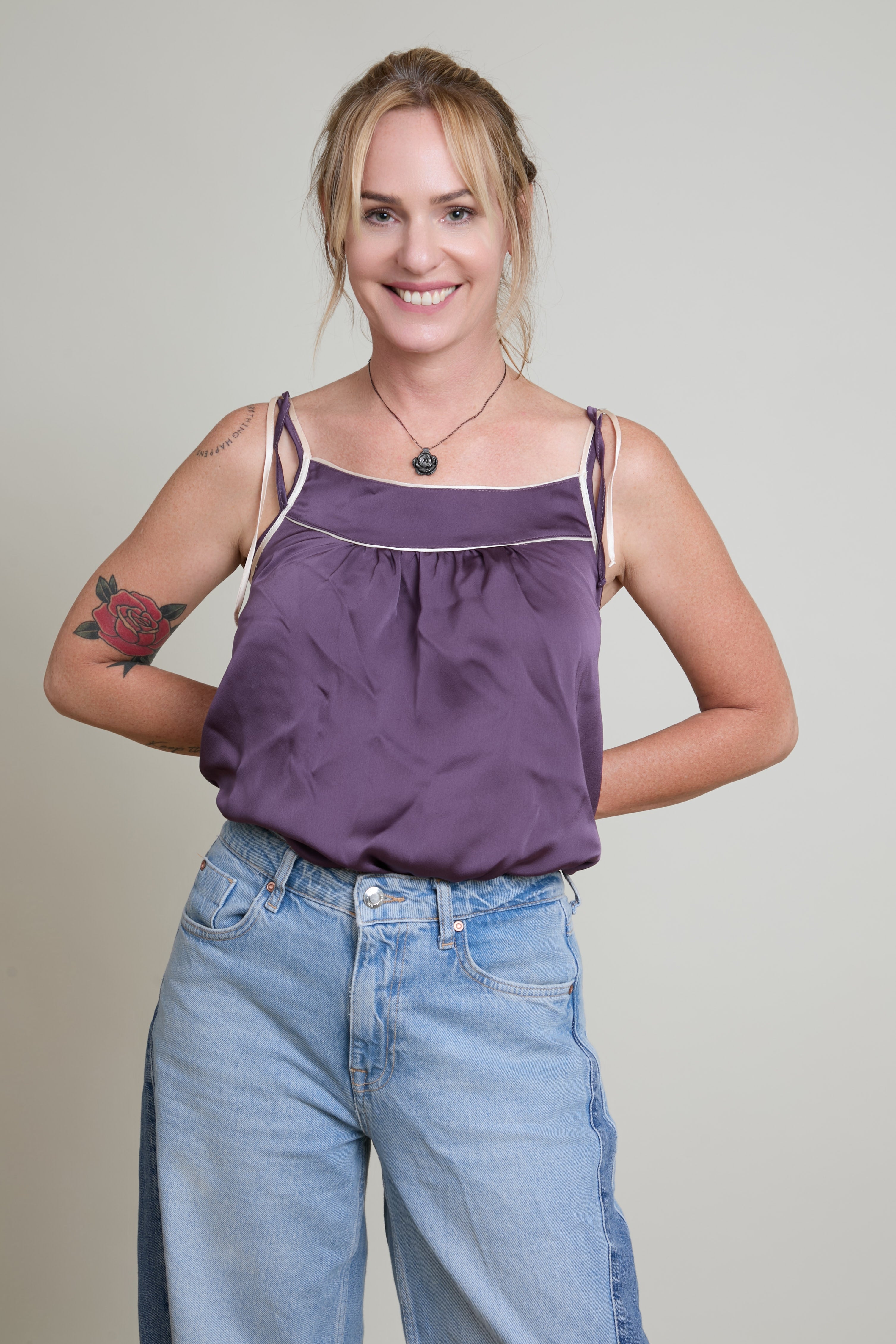 Woman wearing a red tank top with a pink rose design on a plain background