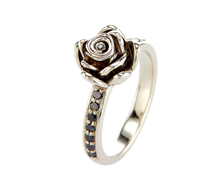 Silver ring with rose design and black gemstones on a white background
