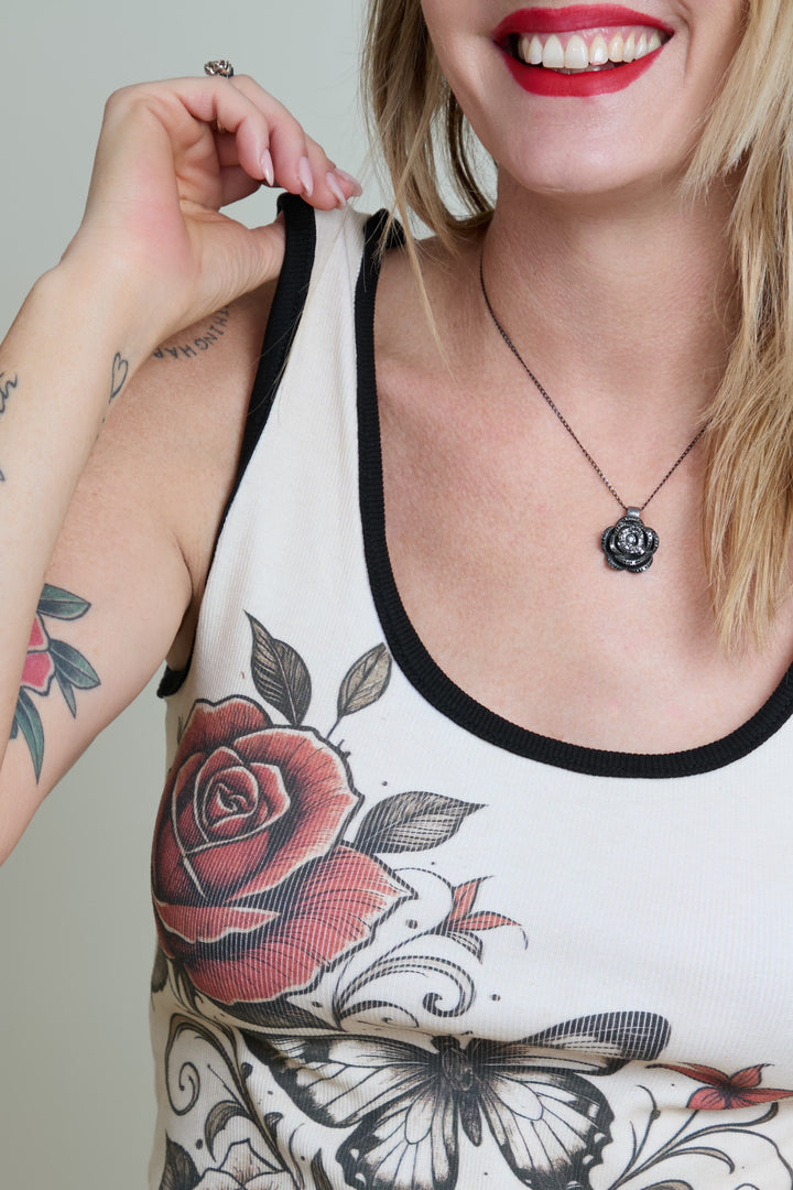 Person wearing a tank top with floral designs and a necklace.