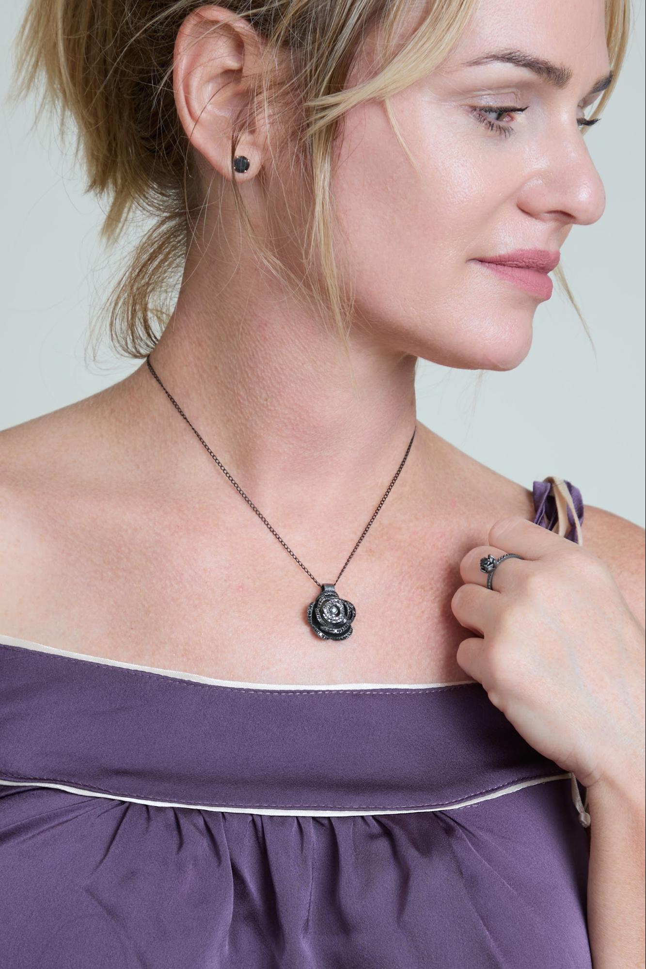 Woman wearing a necklace with a rose pendant, close-up of the necklace.