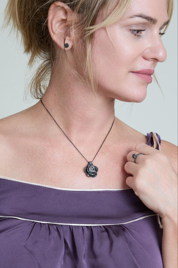 Woman wearing a necklace with a rose pendant, close-up of the necklace.