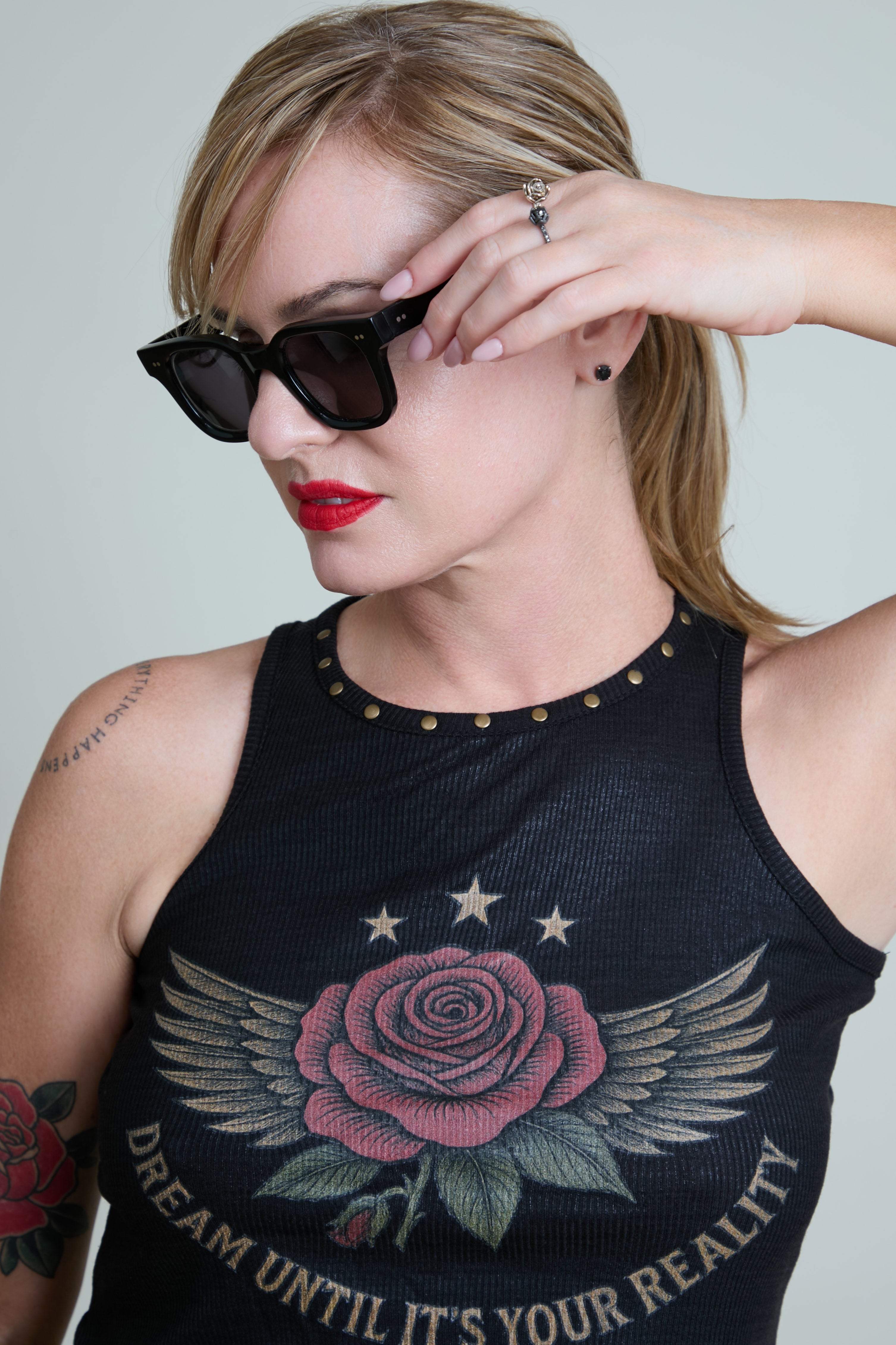 Woman wearing a black tank top with a rose and wings design and text.