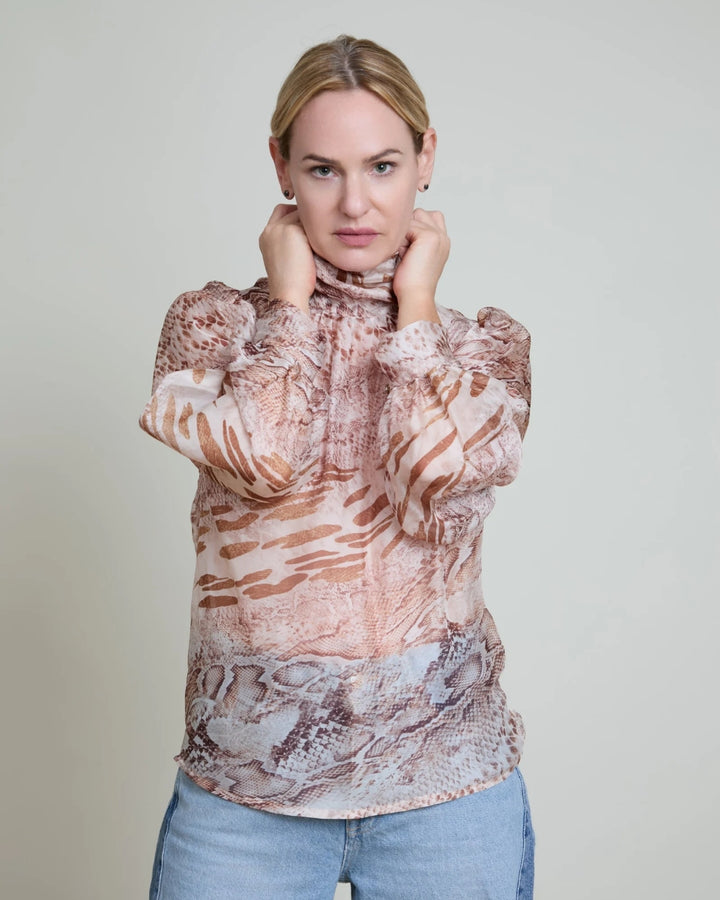 Woman wearing a patterned blouse with a plain background