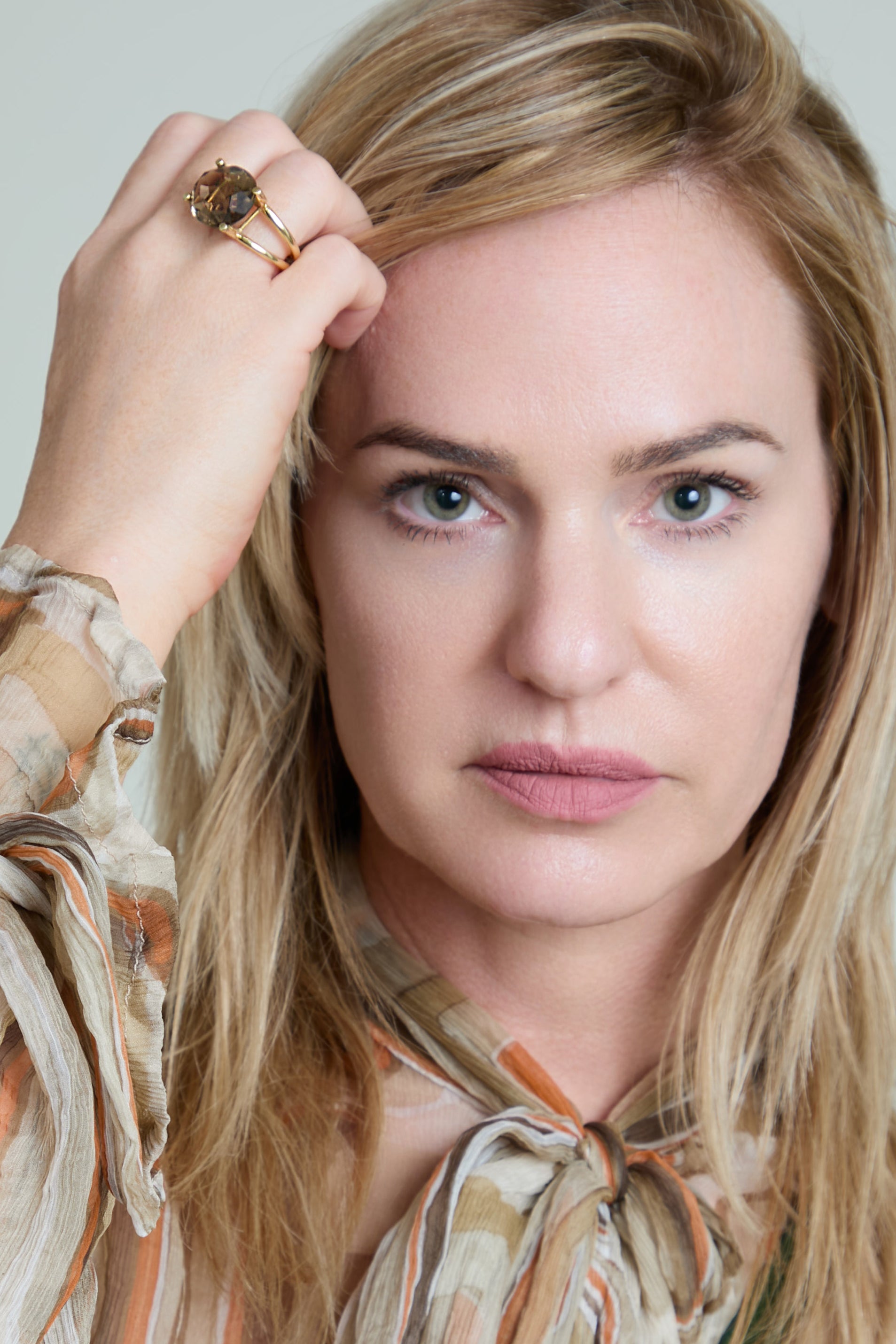 Woman with blonde hair and a patterned blouse against a neutral background