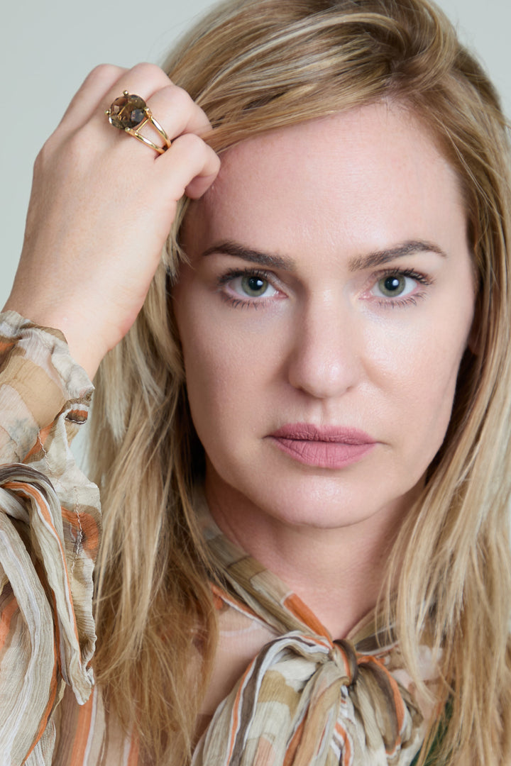Woman with blonde hair and a patterned blouse against a neutral background