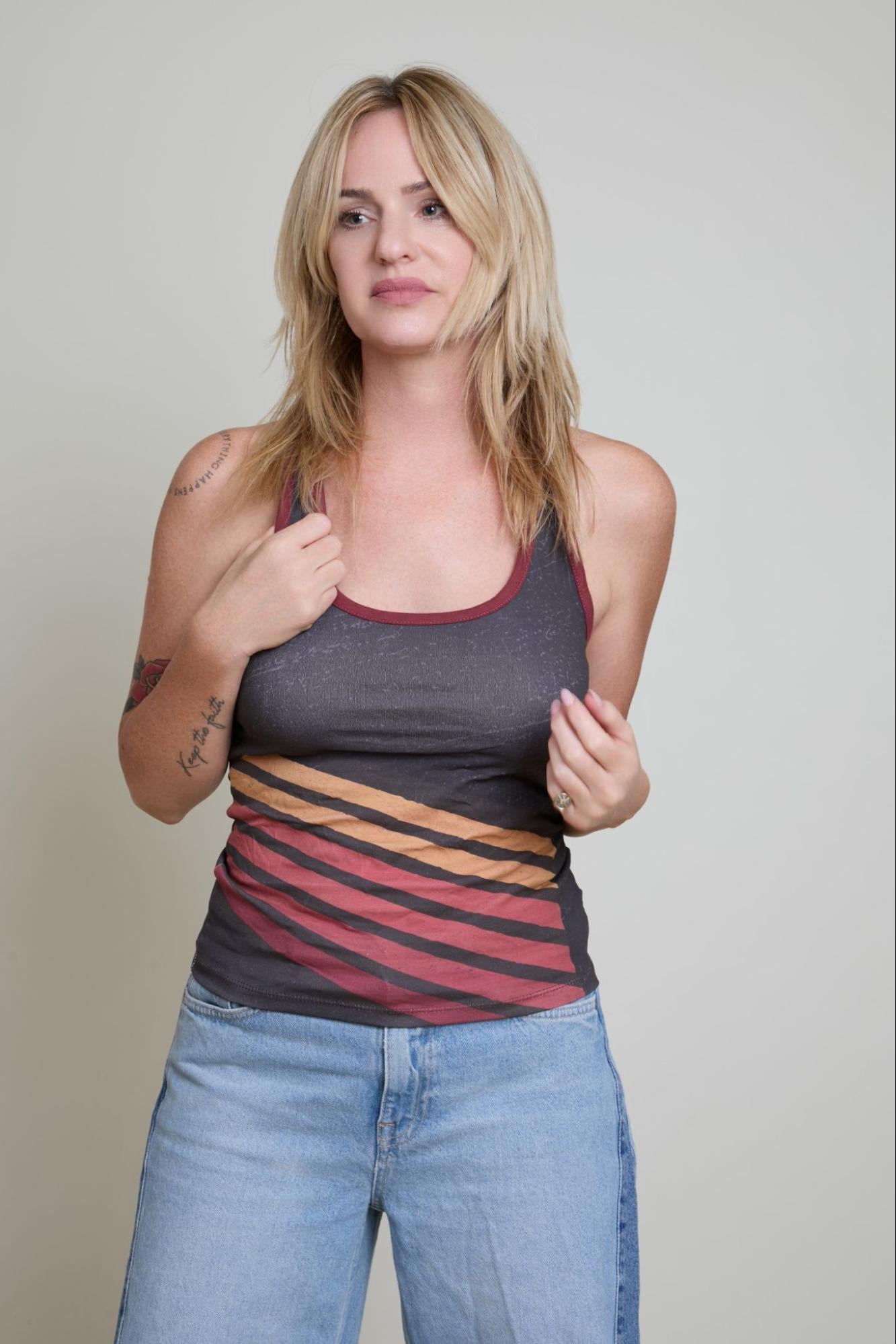 Woman wearing a tank top with a colorful striped design on a plain background