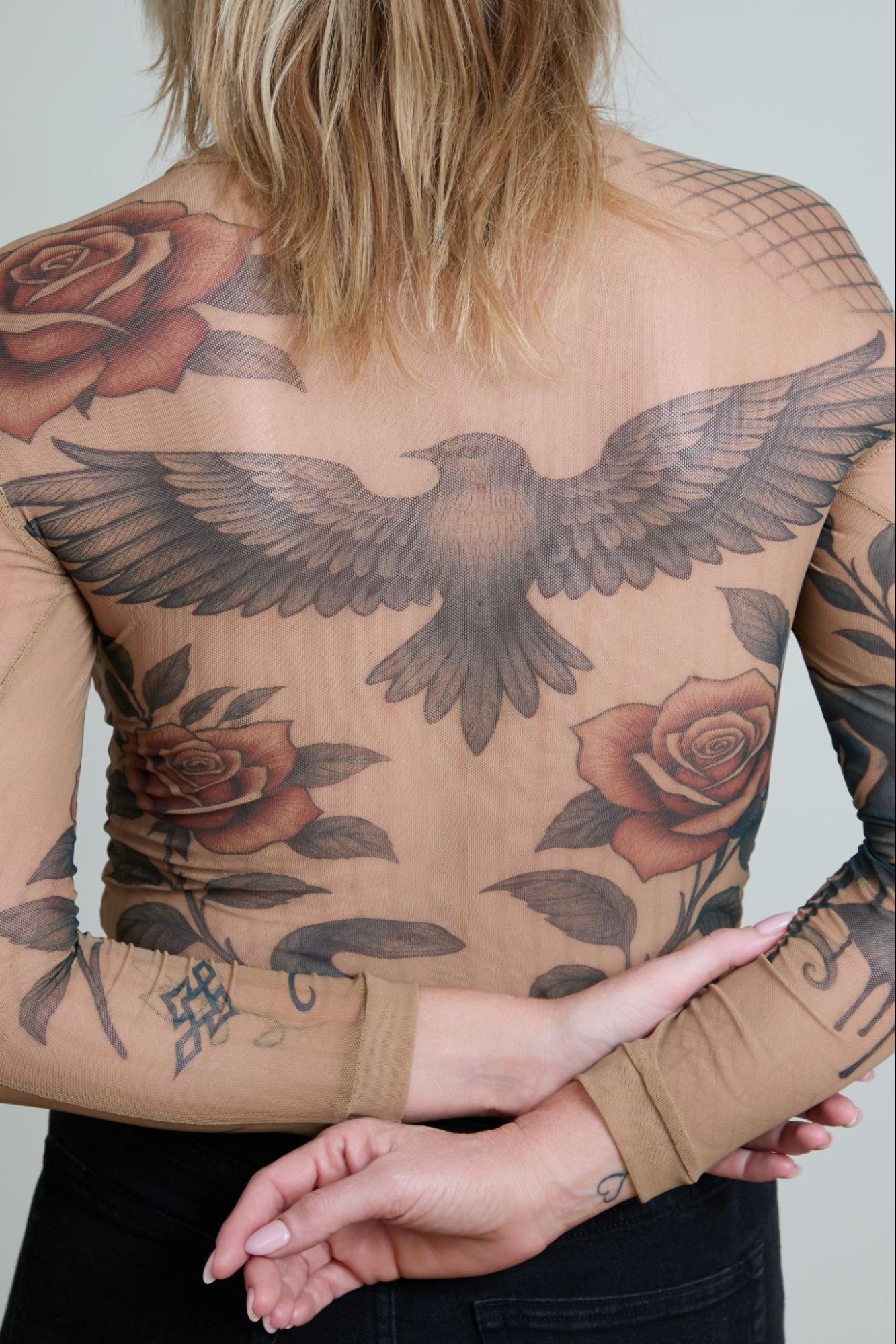 Person with tattoos of an eagle and roses on their back and arms.
