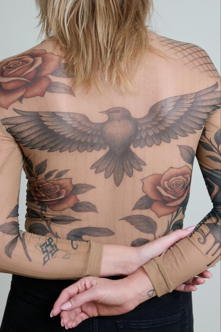 Person with tattoos of an eagle and roses on their back and arms.