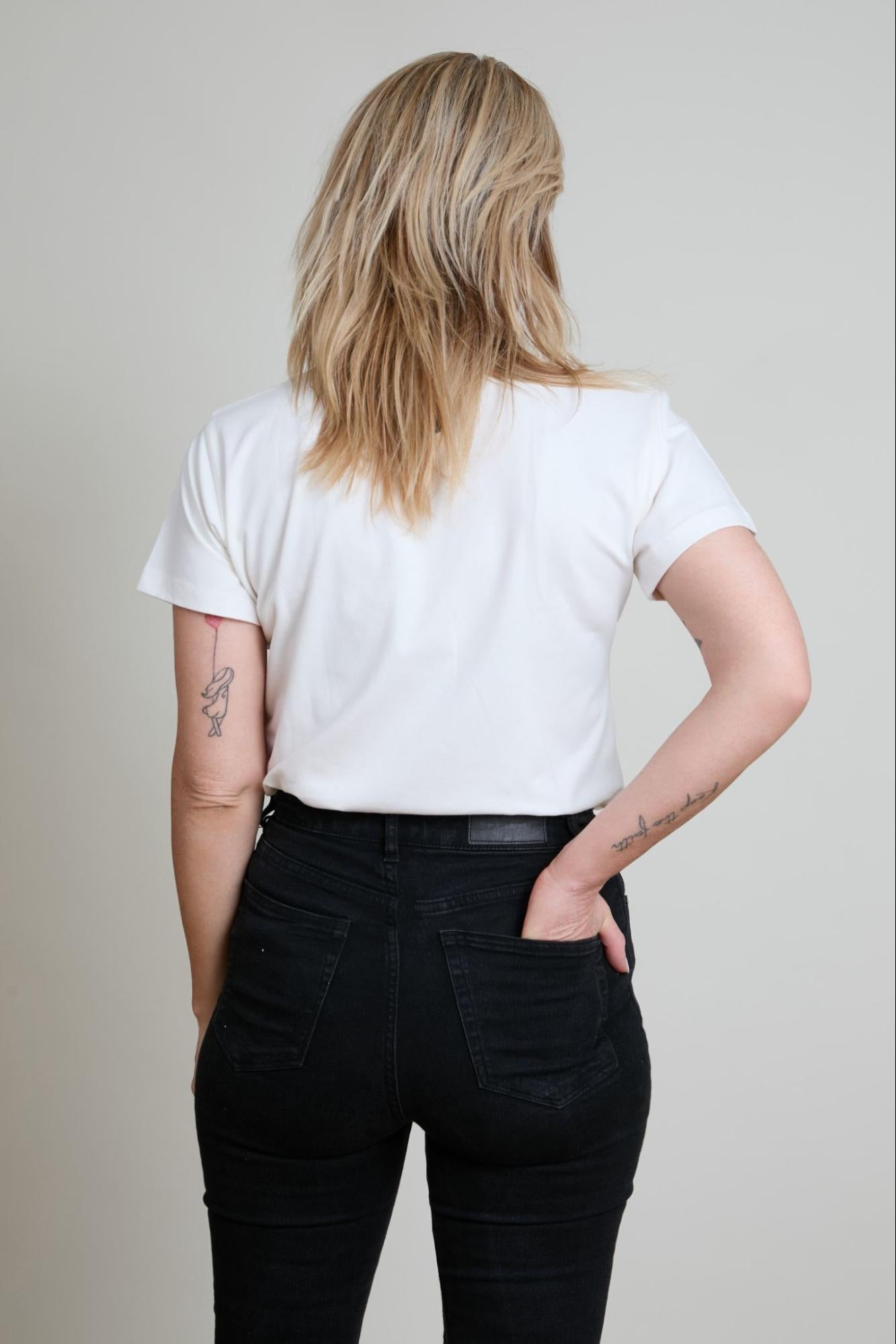 Person wearing a white t-shirt and black pants on a plain background