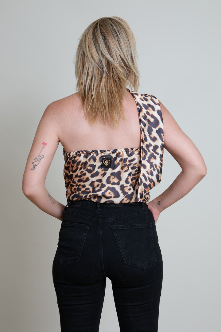 Person wearing a leopard print top and black pants against a plain background
