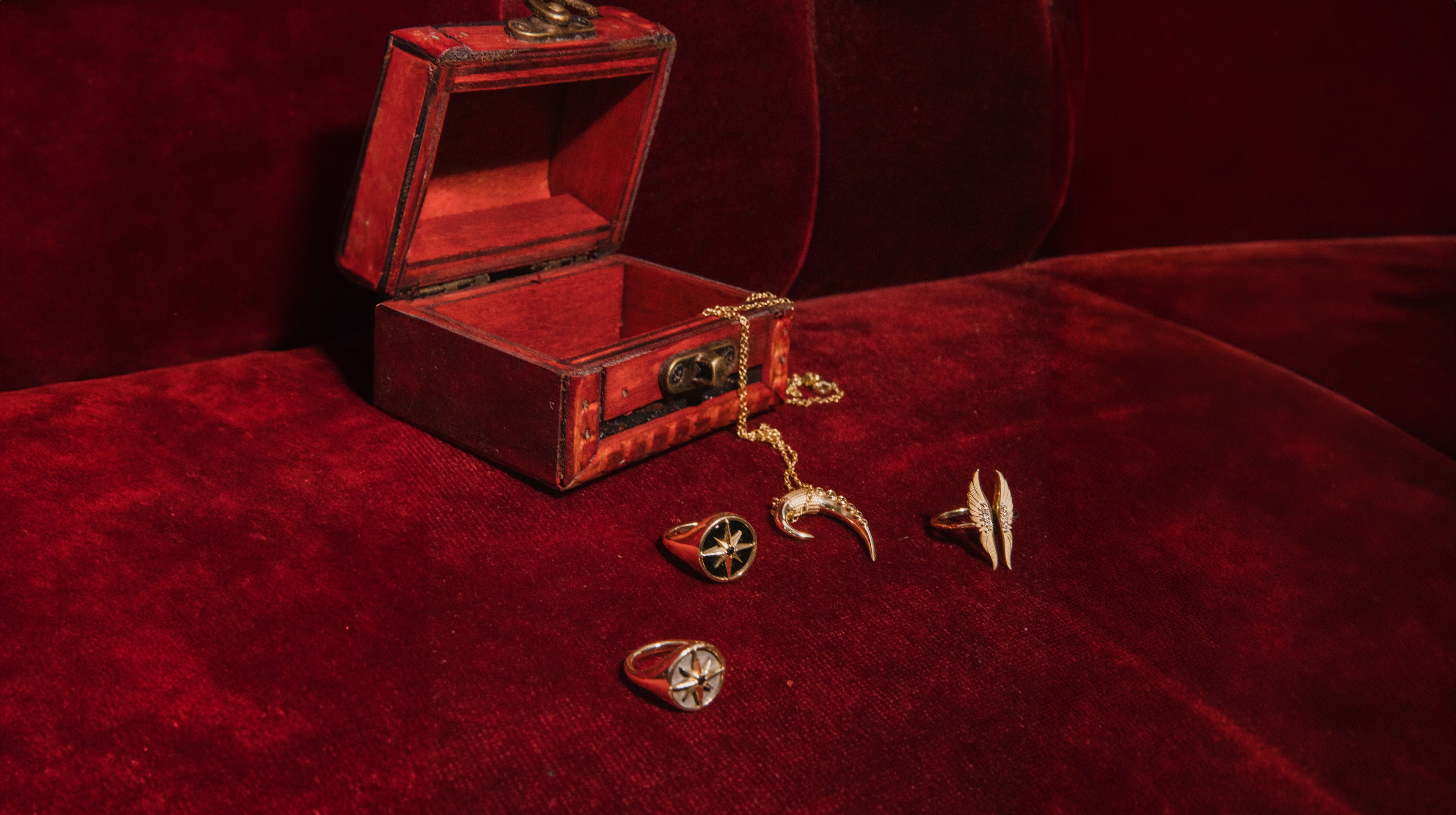 Red jewelry box with gold jewelry on a red velvet surface